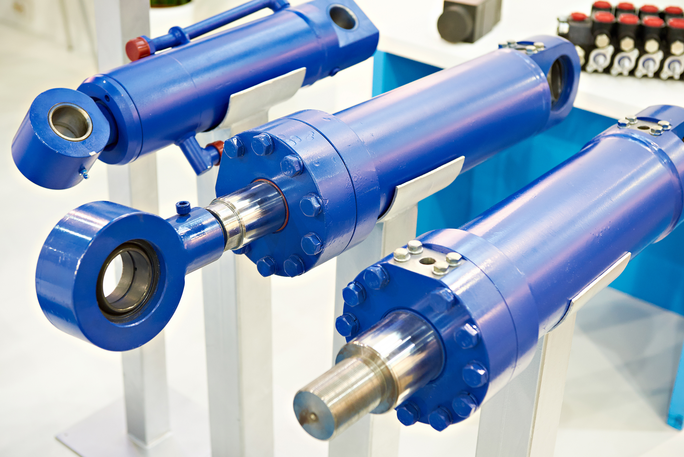 Three blue hydraulic cylinders on display